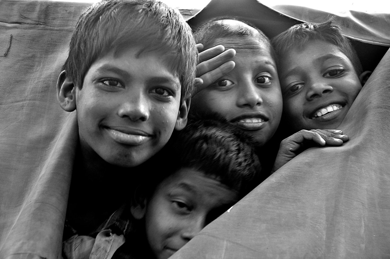Destitute Children Look Through a Torn Canvas of a Police Van at Dhaka City, Bangladesh by Unknown