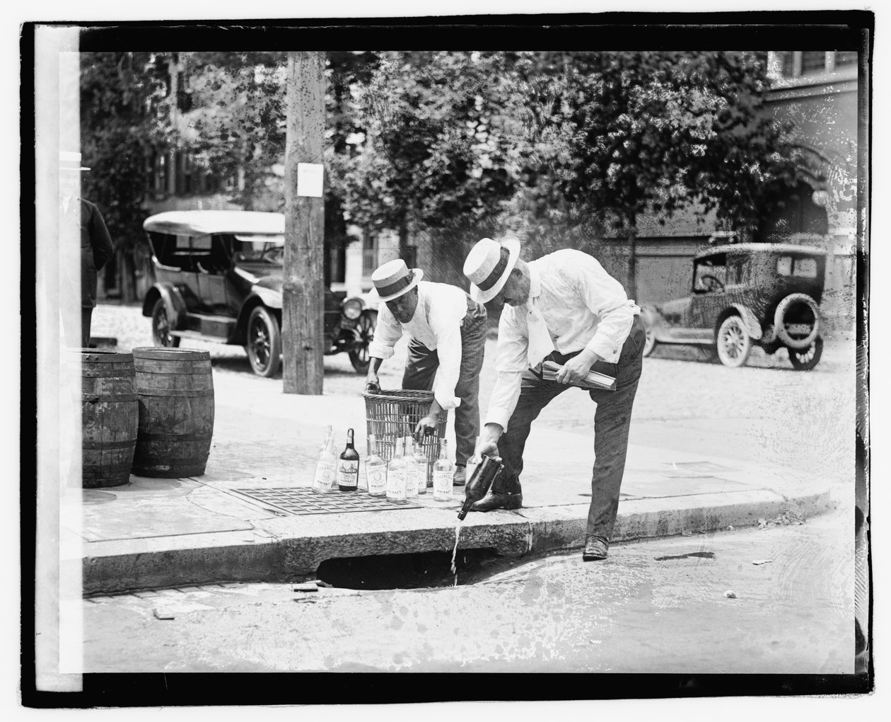 Two Men Pouring Liquor into Storm Drain, 8 July 1921 by American Photographer
