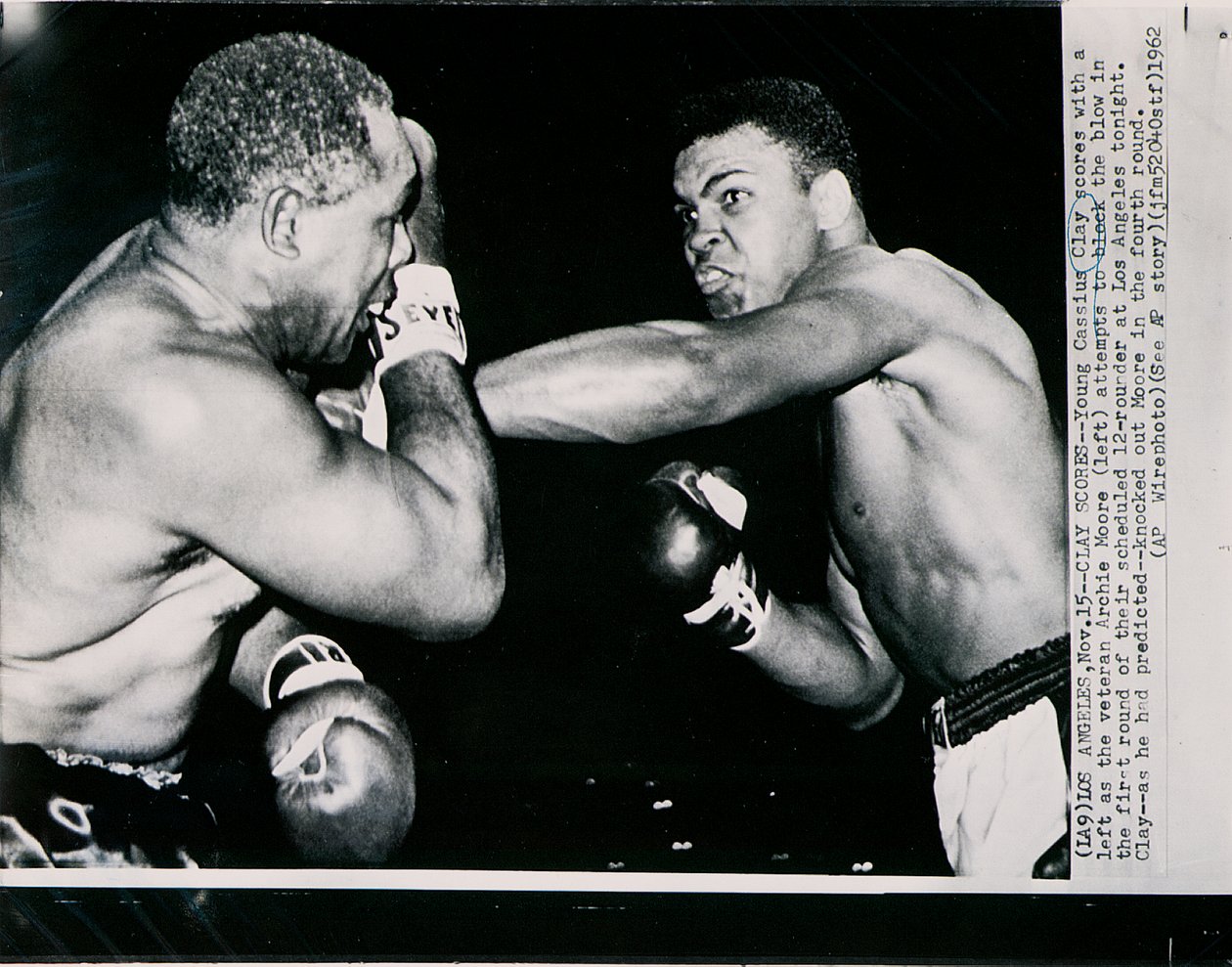 Young Cassius Clay scores with a left against the veteran Archie Moore in the first round of the fight in Los Angeles by American Photographer