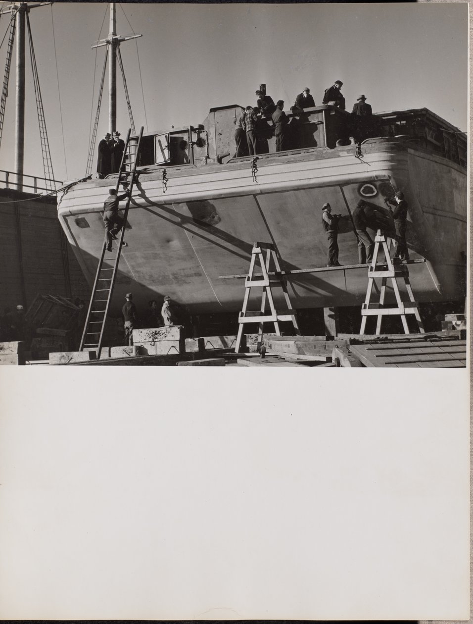 A group of men work on a docked boat by Arnold Eagle