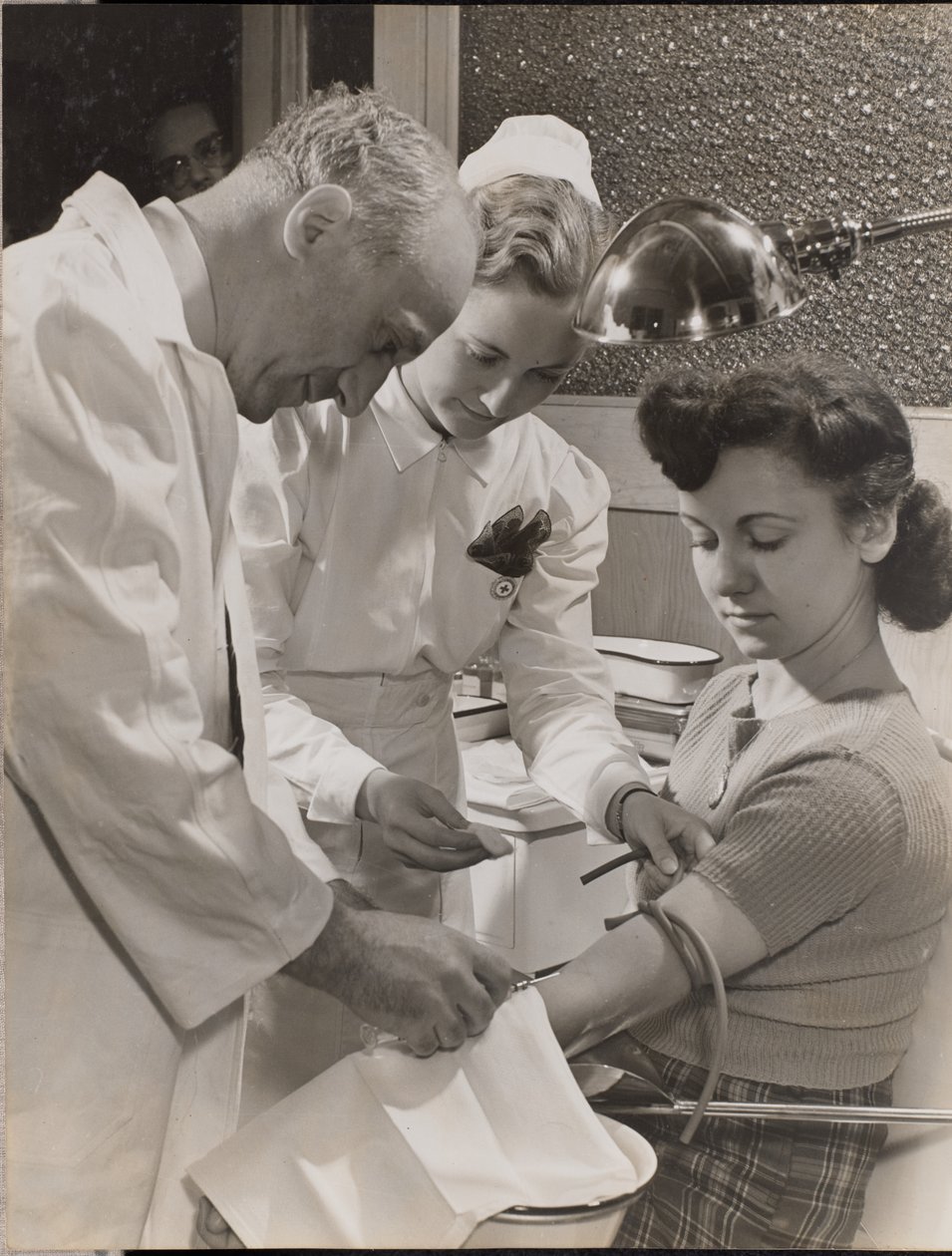 Doctor and nurse inserting a needle into a woman