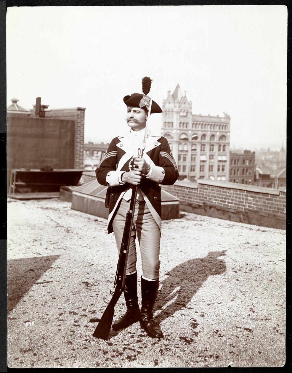 A man on a rooftop dressed in a traditional military uniform, holding a rifle by Byron Company