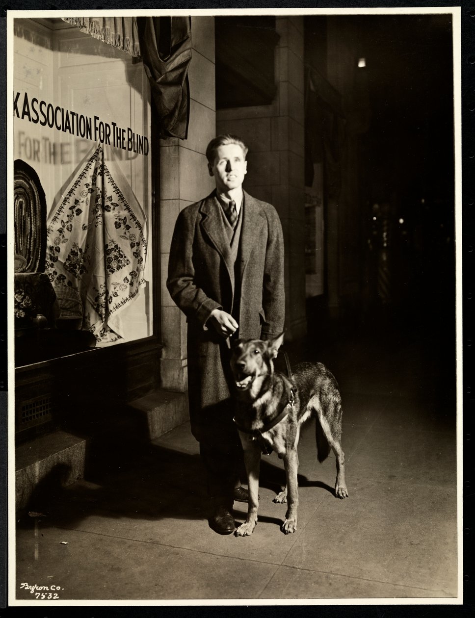 Blind Man and His Guide Dog on the Sidewalk in Front of the New York Association for the Blind, 111 East 59th Street, New York by Byron Company