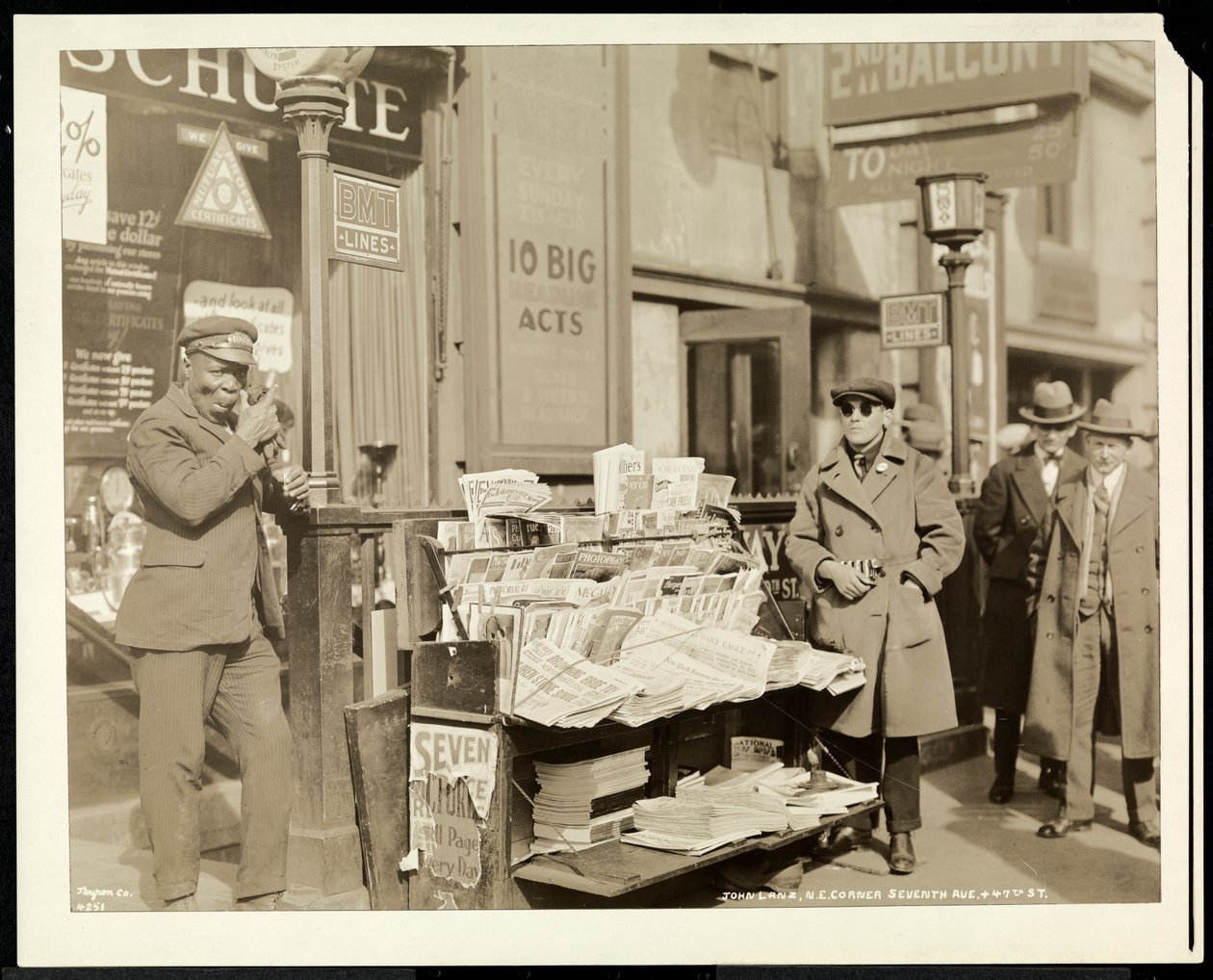 Blind news dealer, John Lanz, at his stand at the north east corner of 7th Avenue and 47th Street, New York, 1926 by Byron Company
