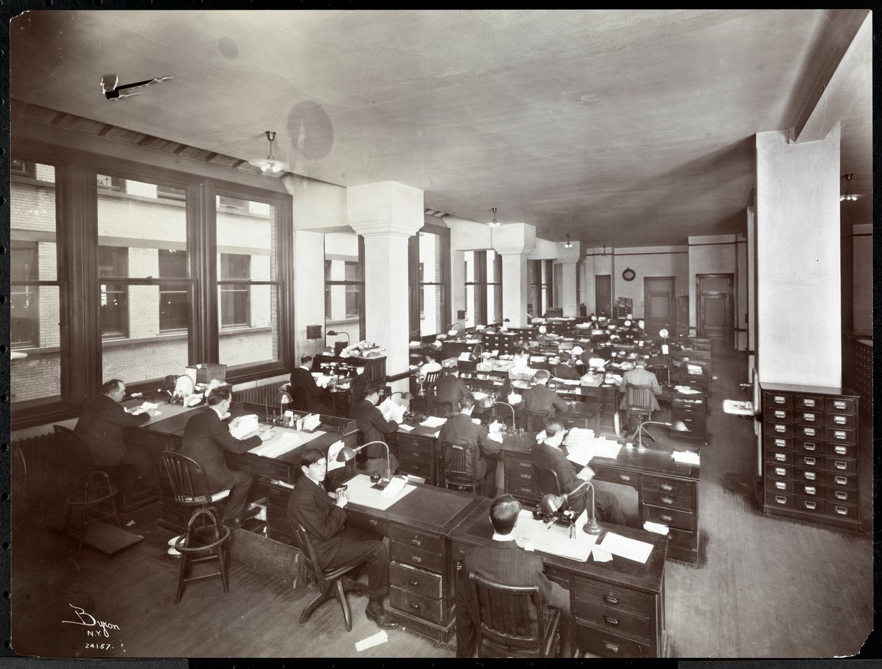 Men and one woman working at desks in an office at the Metropolitan Life Insurance Co. at 23rd Street and Madison Avenue, New York by Byron Company