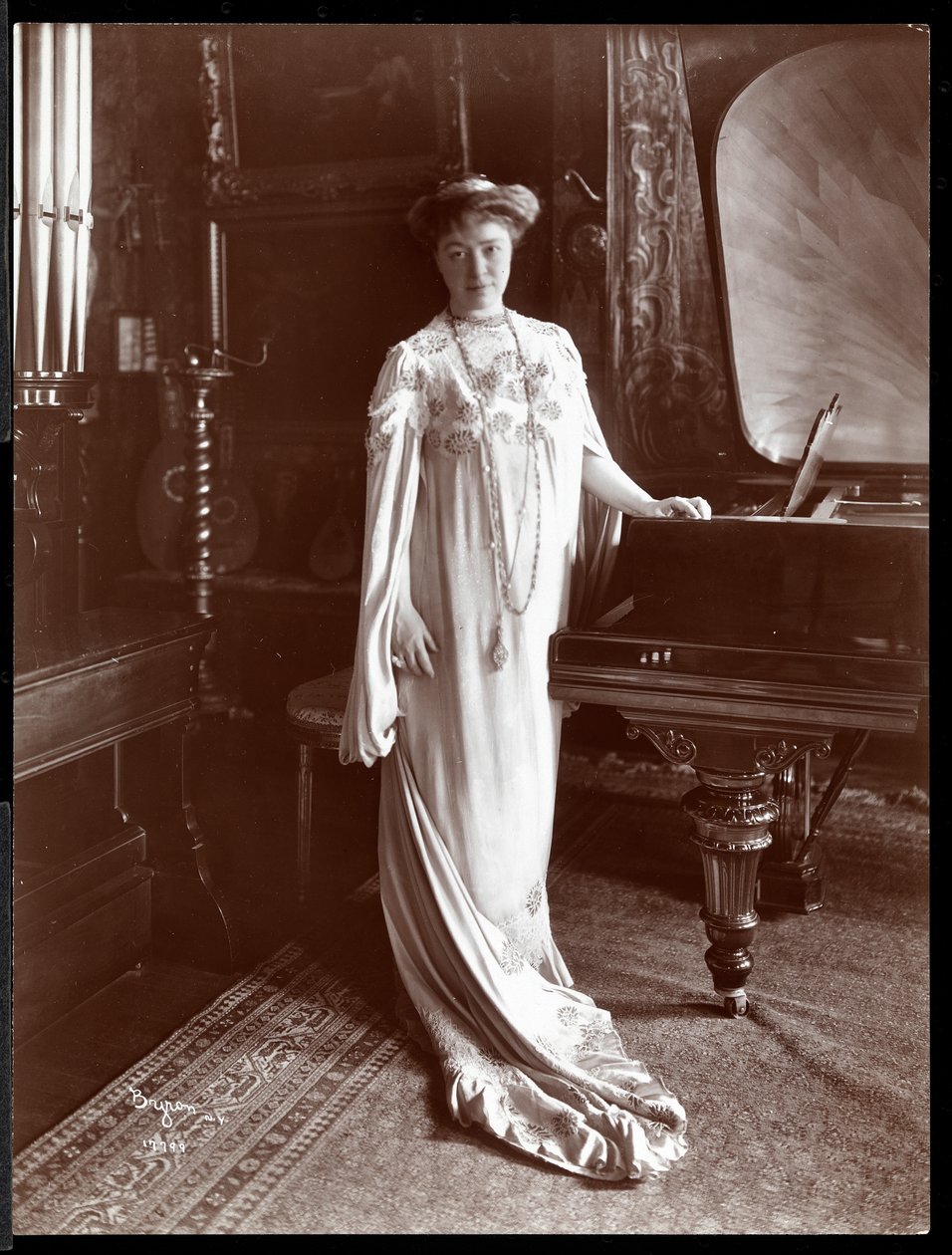Portrait of Mrs. I. M. Clark standing by a piano, 1904 by Byron Company