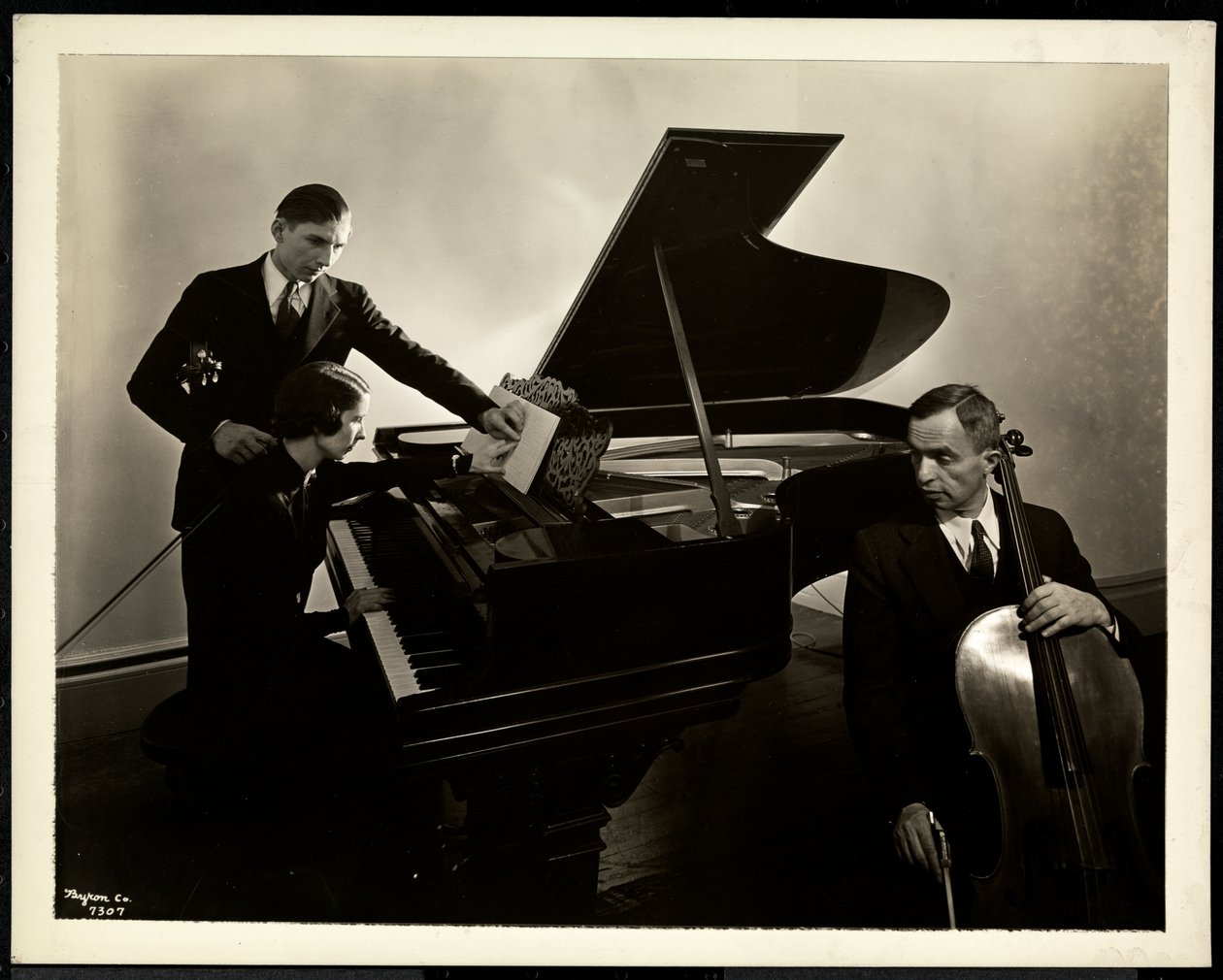 Blind woman, Miss Harding, at the piano instructing two blind men on the violin and cello, 1936 by Byron Company