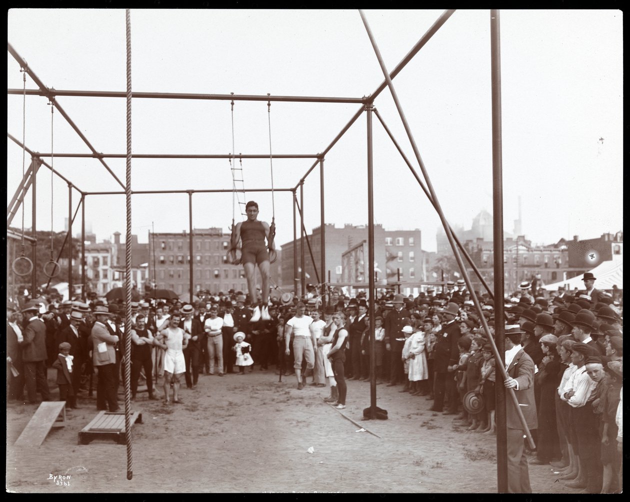 Crowd watching a gymnast at the Hudson Bank Gymnasium and Playground, 53rd Street and 11th Avenue, New York, 1898 by Byron Company