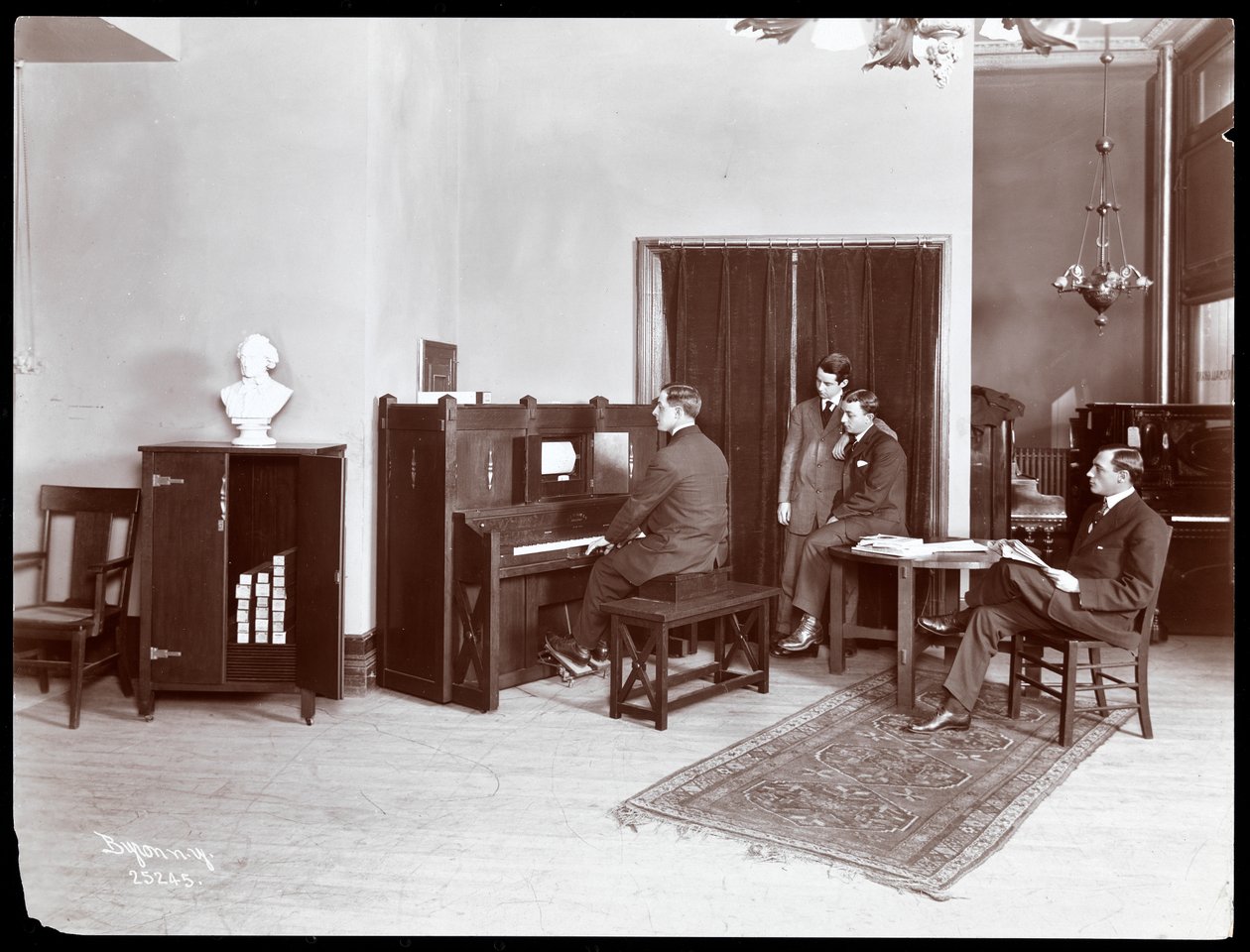Four Men, One Playing an H. Bruman Co. Player Piano, 1907 by Byron Company