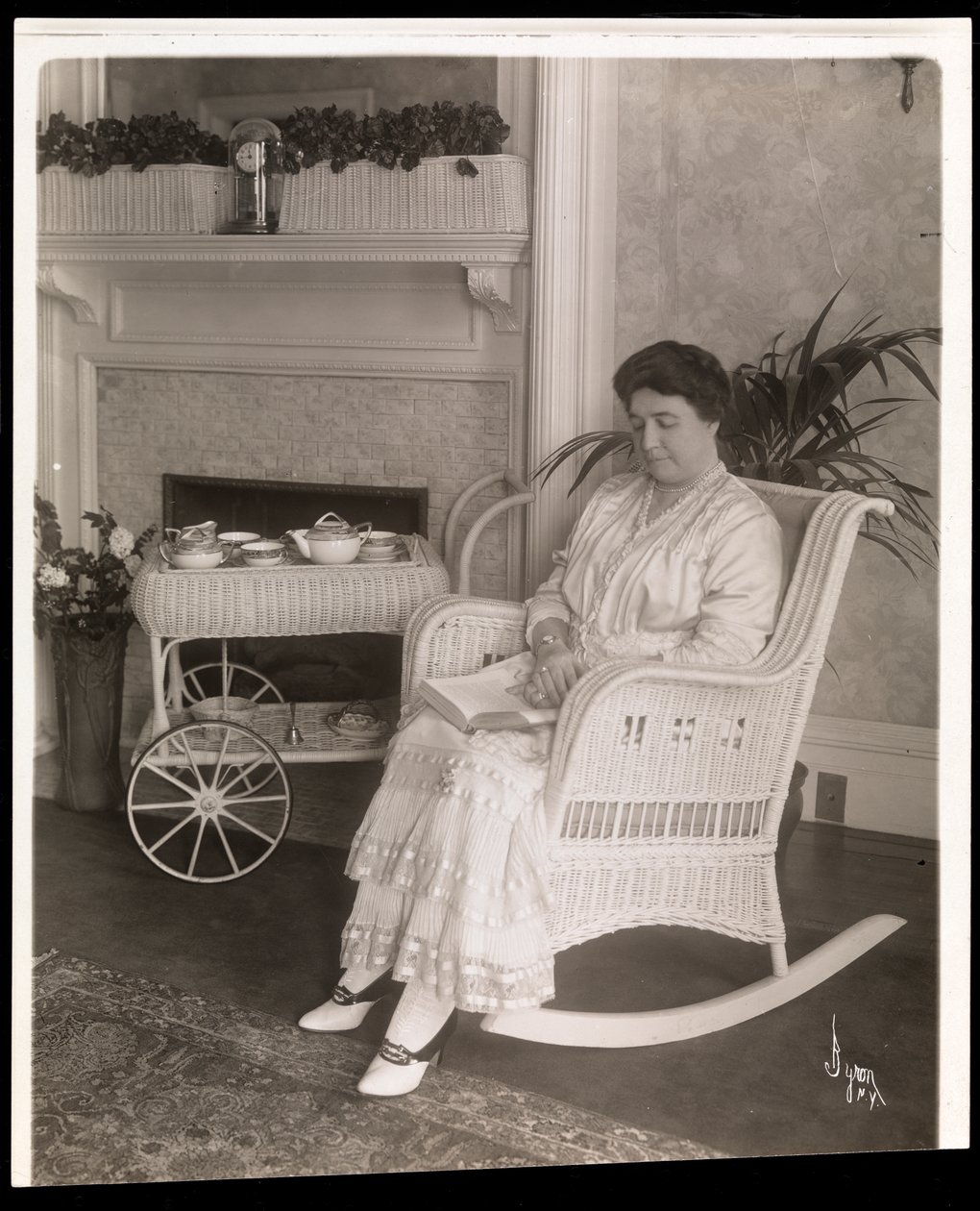 Mrs. Howard Seated with a Book in a Rocking Chair at Her Home at 200, 5th Avenue, New York, 1915-6 by Byron Company