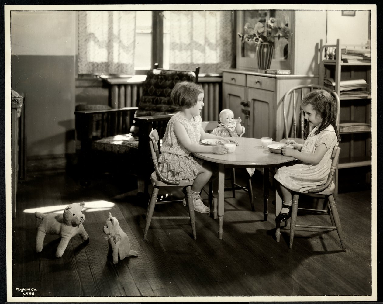 Two blind visually impaired girls eating at a small table with doll at the New York Association for the Blind, 111 East 59th Street, New York, 1933 by Byron Company