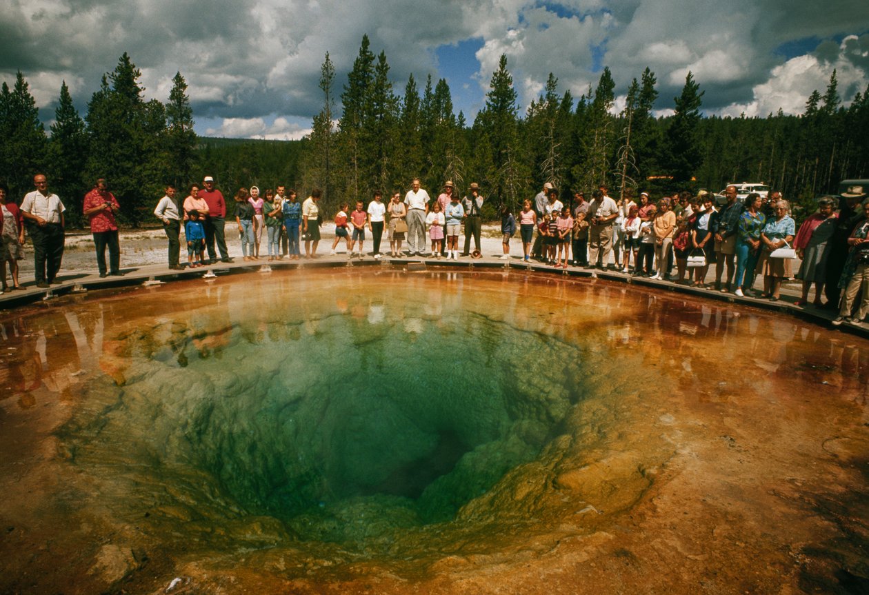 Park visitors gather around blue-green, blossom-shaped thermal pool. Yellowstone National Park by Dean Conger