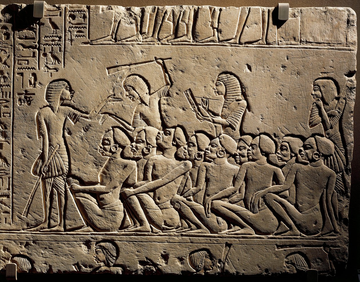 A group of Negroid prisoners surrounded by guards armed with clubs while a scribe draws up a report, relief from the tomb of Horemheb at Saqqara by Egyptian 18th Dynasty