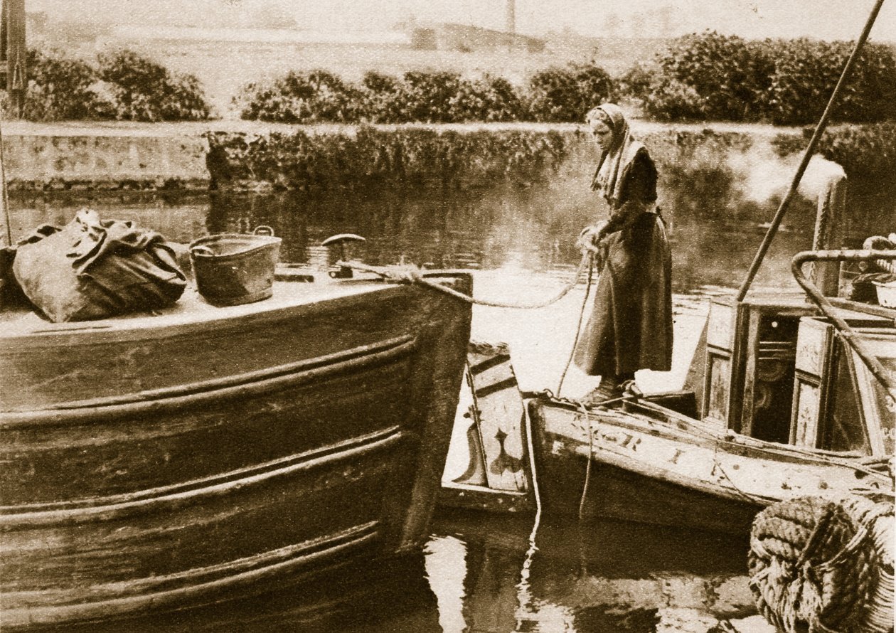 A woman securing the stern of her barge, London by English Photographer