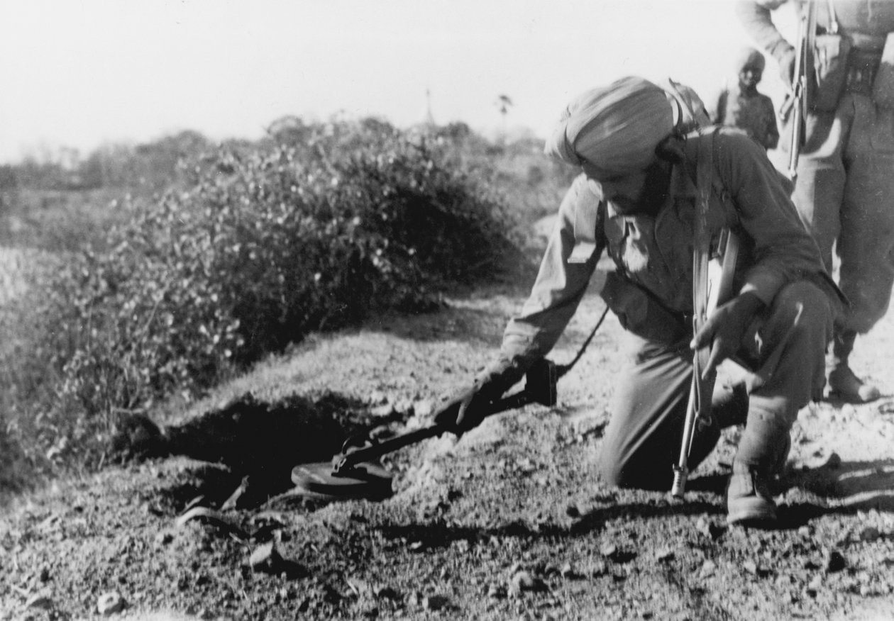 An Indian soldier searching for mines with a metal detector by English Photographer