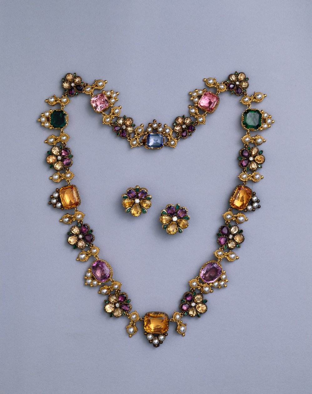 A fine Regency gold and jewelled necklace set with cushion-cut topaz, amethysts, pink tourmalines, emeralds, sapphires and peridots, with a pair of flowerhead earrings, c.1810 by English School