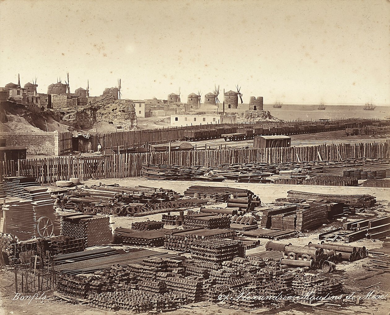 Yard for construction materials, windmills are in the background, in Alexandria, Egypt by Félix Bonfils