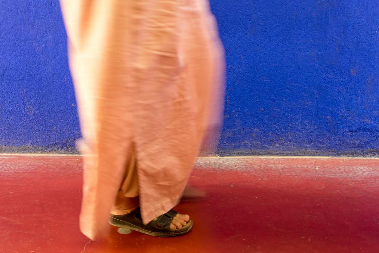 Walking past a blue wall in the Majorelle Garden, Marrakech, Morocco by Ira Block