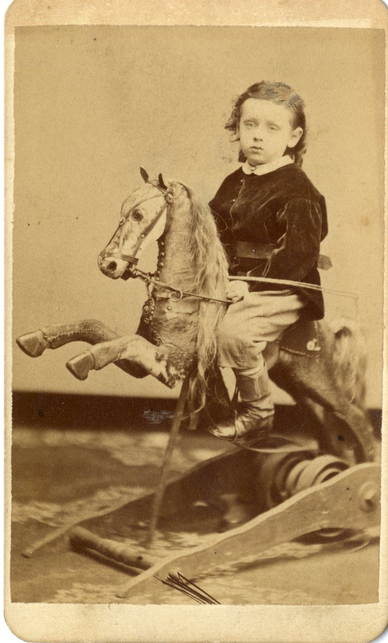Young boy with whip on rocking horse by John McCaffrey