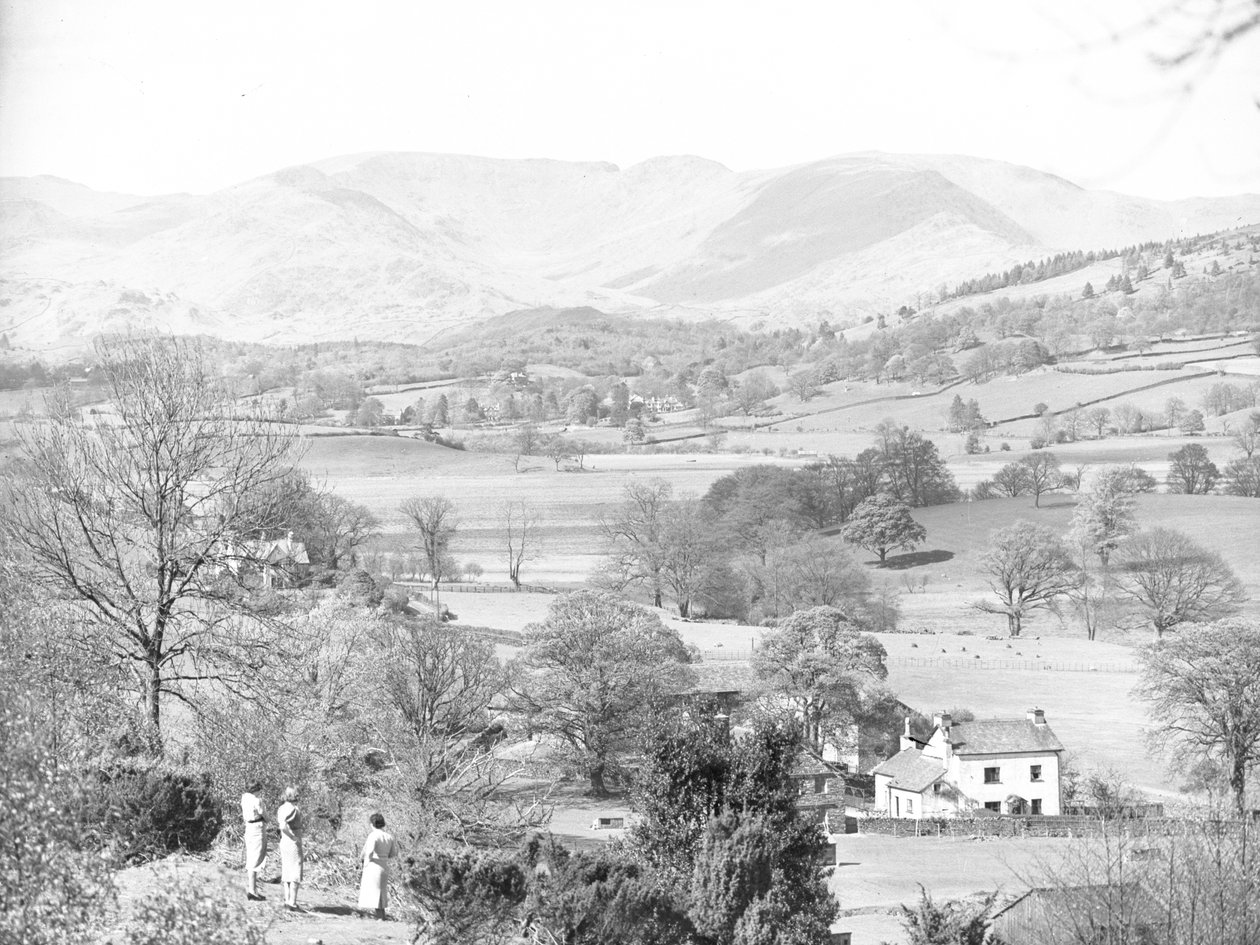 Three women standing looking out across a lake at Esthwaite, hills in the background by Joseph Hardman