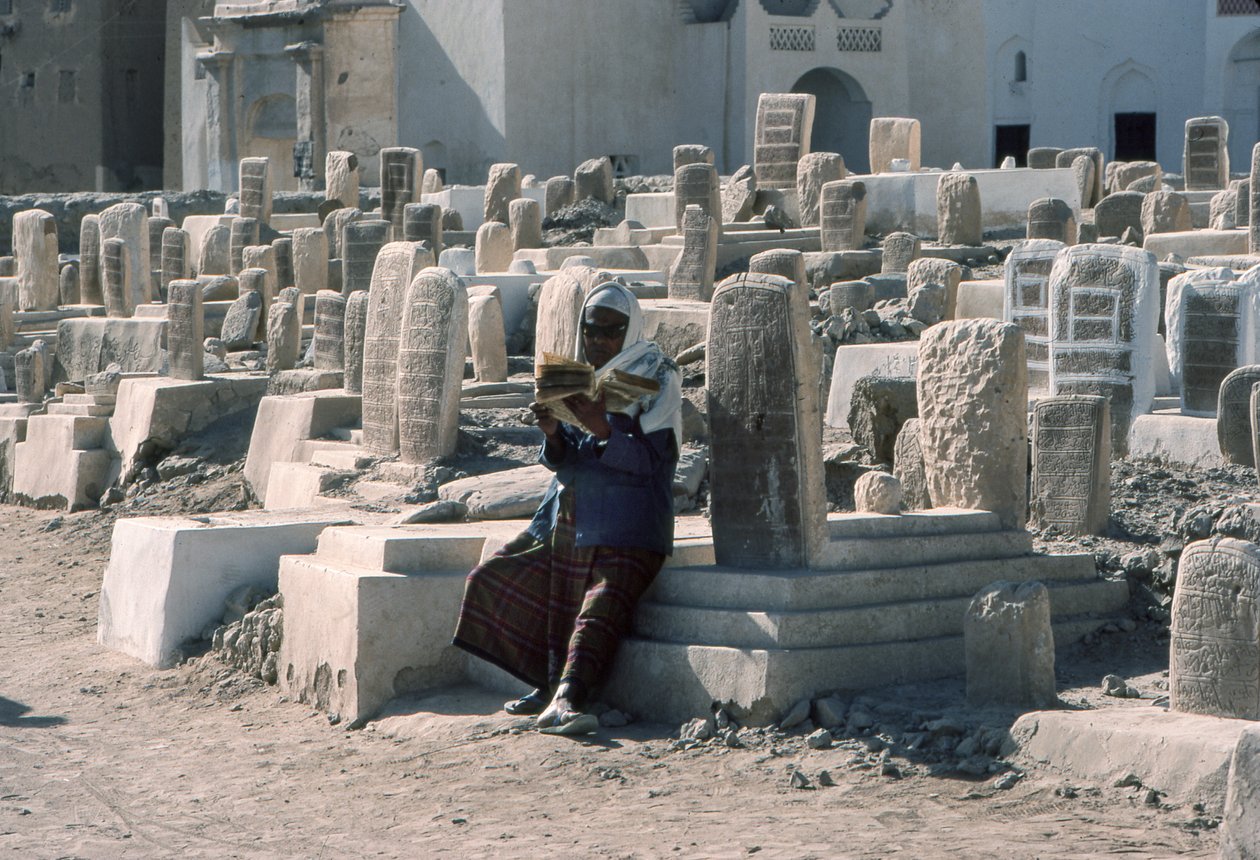 Yemenite man recites the Koran in cemetery with tombs at Sayun, Hadramawt, South Yemen by Lynn Abercrombie