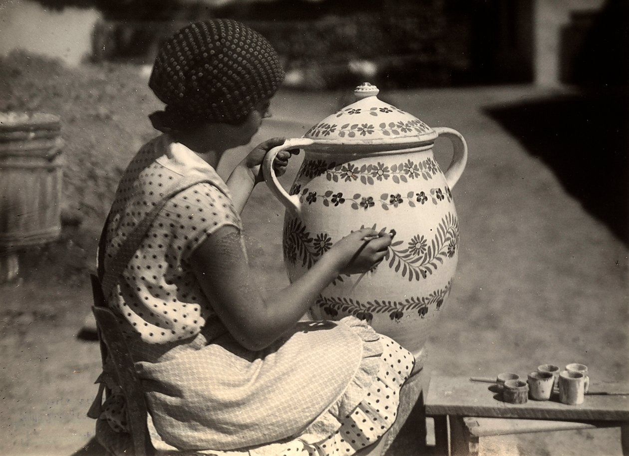 A Hungarian lady painting an amphora with floral motifs by Rudolf Balogh