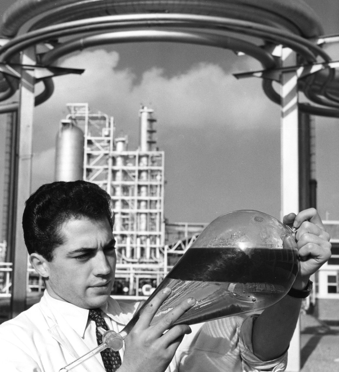 A laboratory worker holds a separating funnel of oil, Dunkirk refinery, France, 1950s by Unbekannt