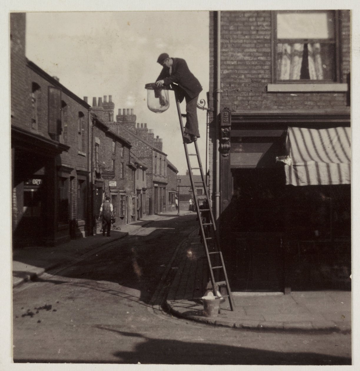 Man cleaning a gas street light, c 1905 by Unbekannt