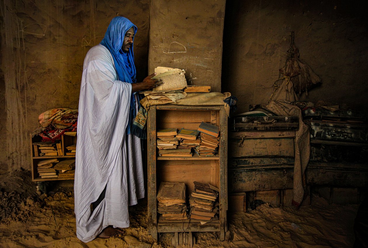 Man flips through a priceless manuscript in his sandy house, 2009 by Unbekannter Künstler