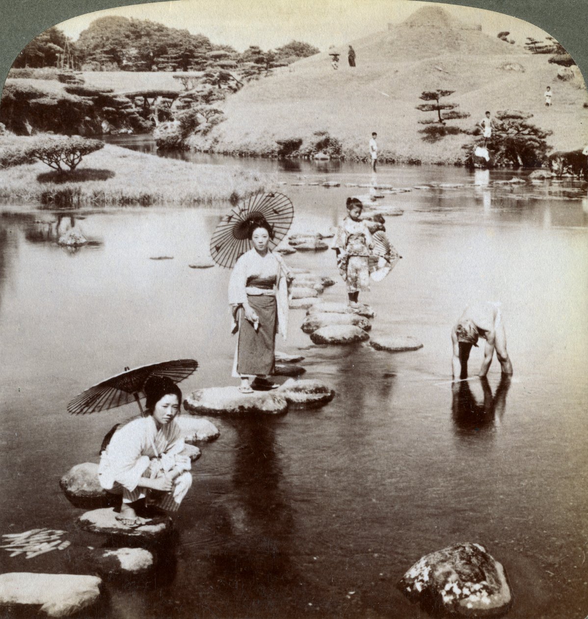 Women Crossing the Lake on Stepping Stones, Suizen-ji Garden, Kumamoto, Japan by Underwood and Underwood