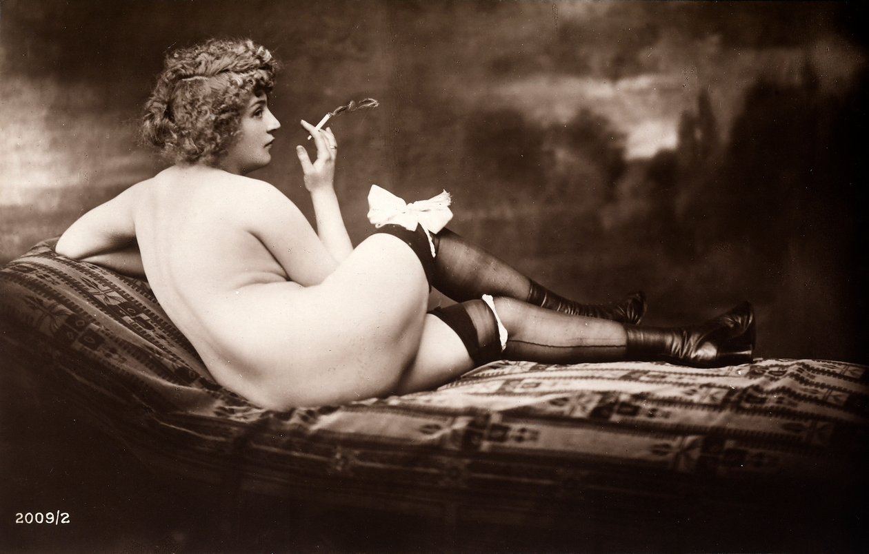 Portrait of a young woman posing naked, with her back turned, as she smokes a cigarette by Unknown photographer