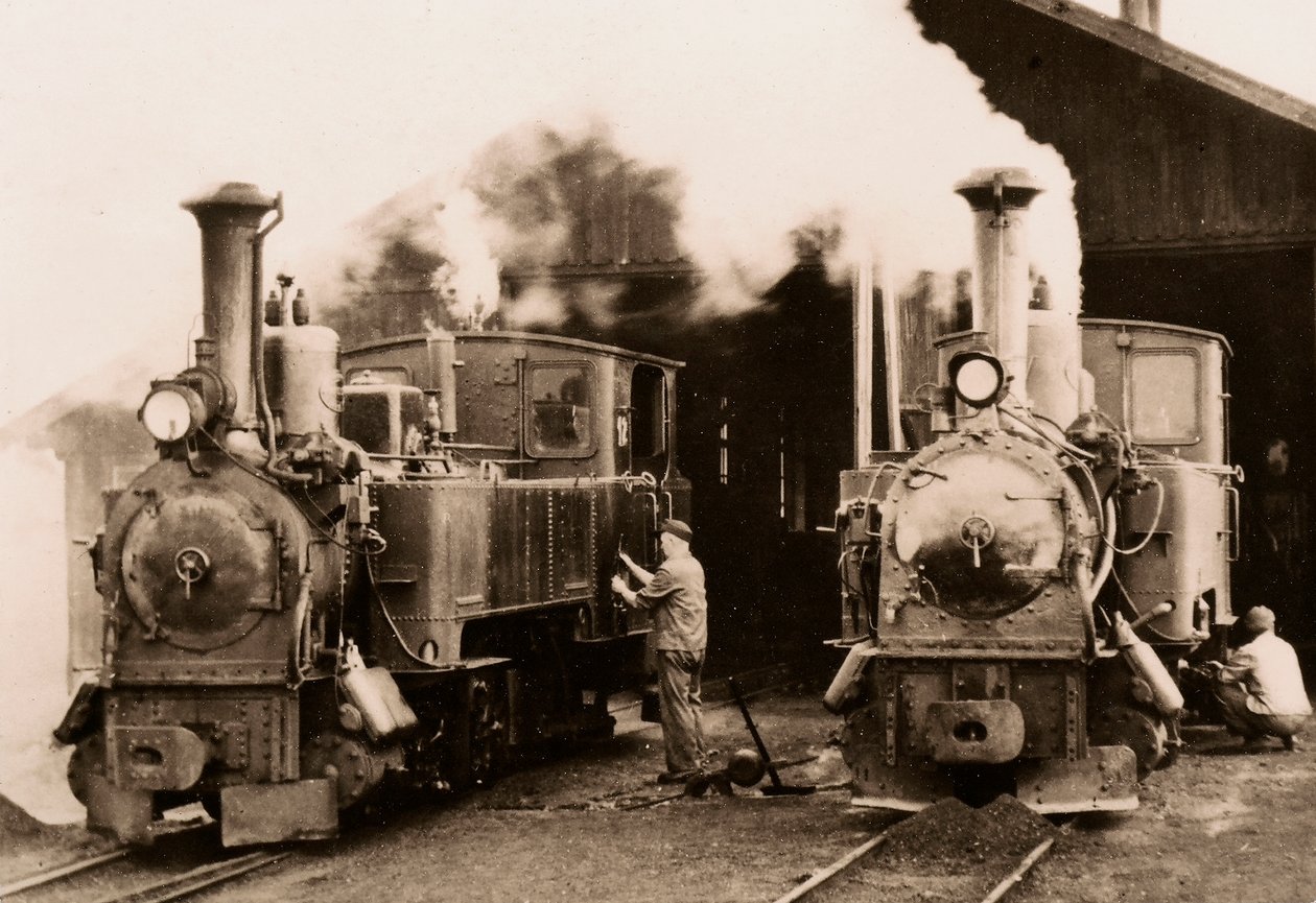 Two steam locomotives being maintained by two workers by Unknown photographer