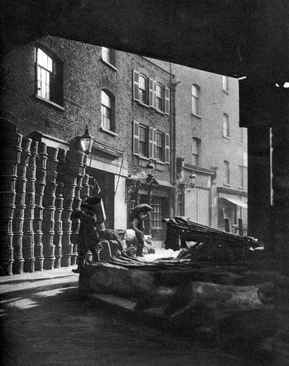 Fruit baskets piled against houses at Borough Market, London, 1926-1927 by Whiffin