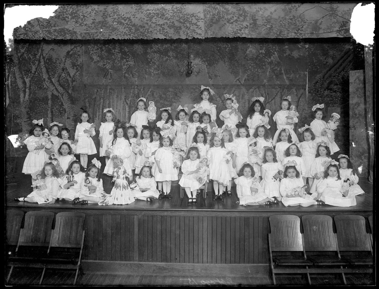 Group of Little Girls Posed on a Small Stage Holding Dolls, Probably the Roman Catholic Orphan Asylum, Kingsbridge, Bronx, c.1911 by William Davis Hassler