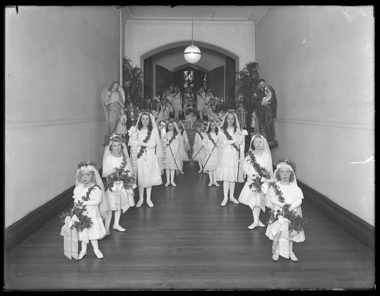Little girls at the Roman Catholic Orphan Asylum, Kingsbridge, Bronx, coming back from chapel in white dresses with wreathes and garlands, October 20, 1914 by William Davis Hassler