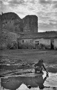 Young Girl Playing with a Paper Boat in a Puddle Surrounded by Mud, Venosa, Basilicata, Italy