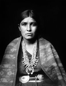 Navajo woman wearing silver squash blossom necklace, concho belt, blanket draped over shoulders, photo Edward S. Curtis