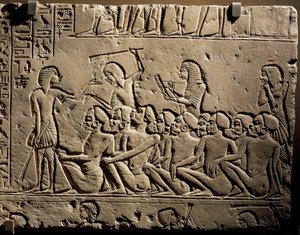 A group of Negroid prisoners surrounded by guards armed with clubs while a scribe draws up a report, relief from the tomb of Horemheb at Saqqara