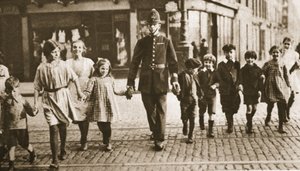 A bobby on the beat helping children across the street at the end of the  school day, from Wonderful London, published 1926-27
