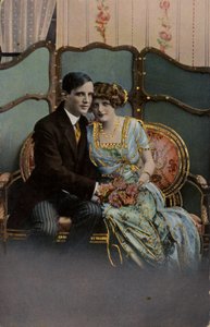 Couple holding a bouquet of flowers, seated on a loveseat