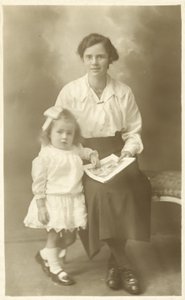 Pretty girl, mother or governess, showing photos to young child by English Photographer