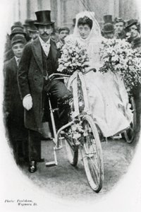 Roman Catholic couple leaving Notre Dame de France, Leicester Square, on bicycles by English Photographer