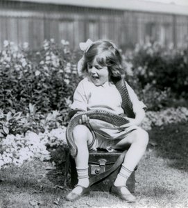 A young girl Betty holding an Eastern Indigo Snake, while sitting on a leather trunk, London Zoo, 1924 by Frederick William Bond