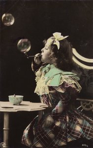 A little girl blowing bubbles from a pipe