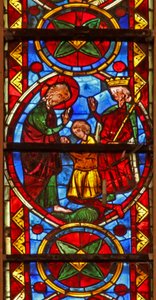 Window w213 depicting a scene from the life of St Thomas: the saint at a marriage banquet for the daughter of the king of India has his face slapped by a cupbearer; a lion removes his arm by French School