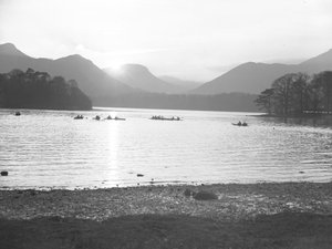 A view of people canoeing on Derwentwater at either sunrise or sunset