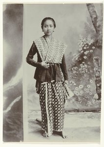 Studio portrait of a young Javanese woman in a sarong with batik motif and a checkered shirt by Kassian Cephas