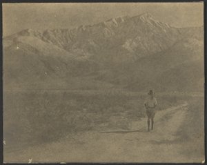 Woman Walking on Path Towards Mountains by Louis Fleckenstein