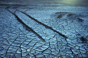 Photograph of a dried bed of chemical sludge patterns and tracks from a car or truck