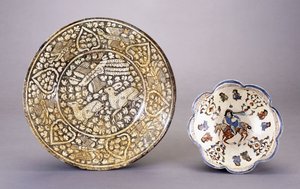 A Sultanabad pottery dish, depicting two seated deer amongst dense leafy motifs by Persian School